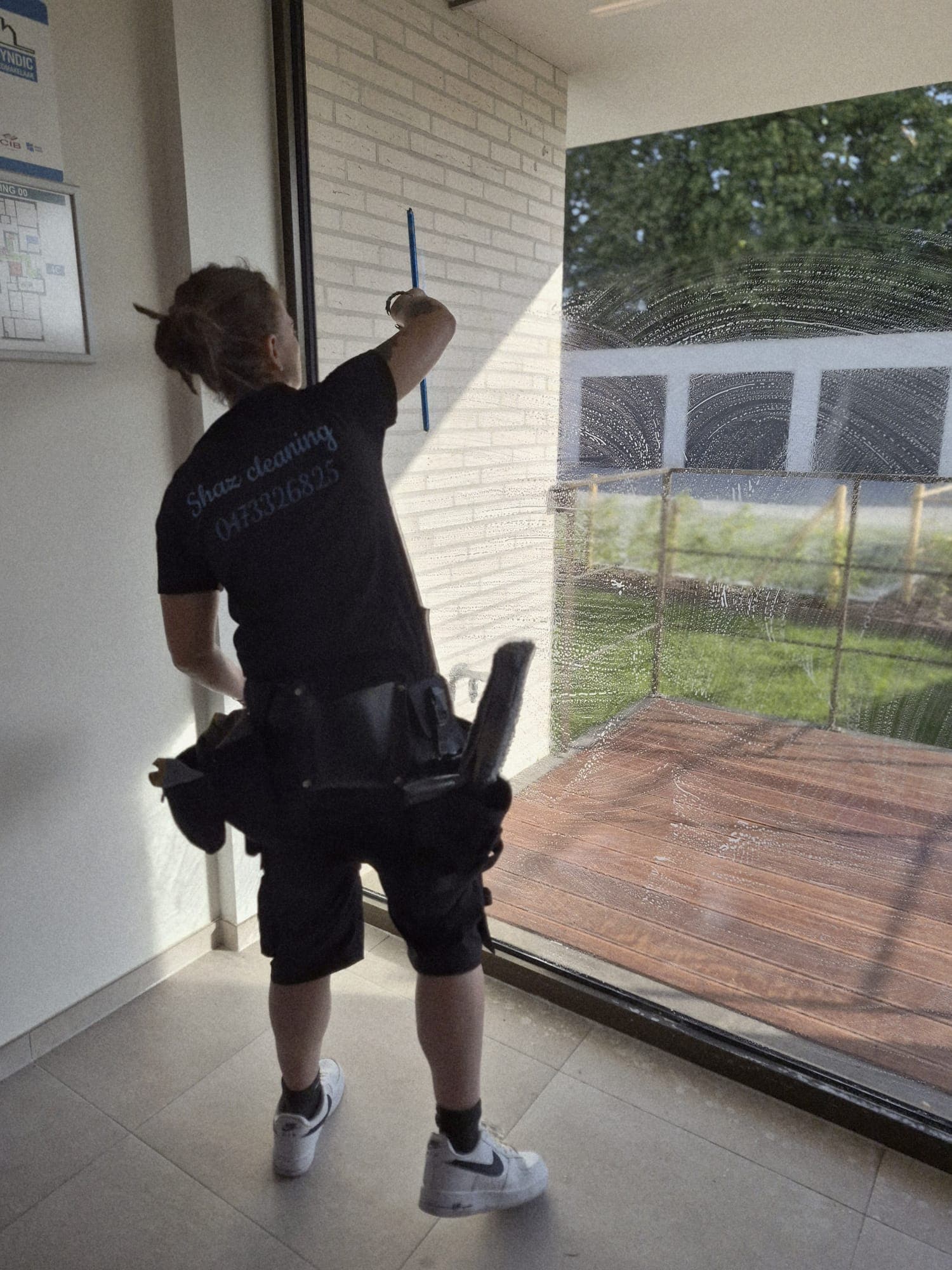 Medewerker van Shaz Cleaning poetst een raam met trekker