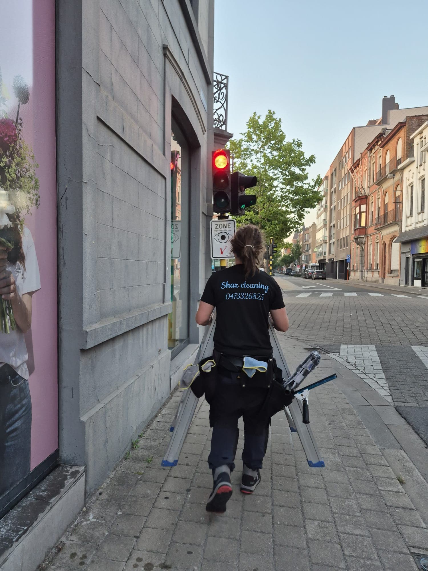 Medewerker van Shaz Cleaning met ladder en toolbelt in de stad