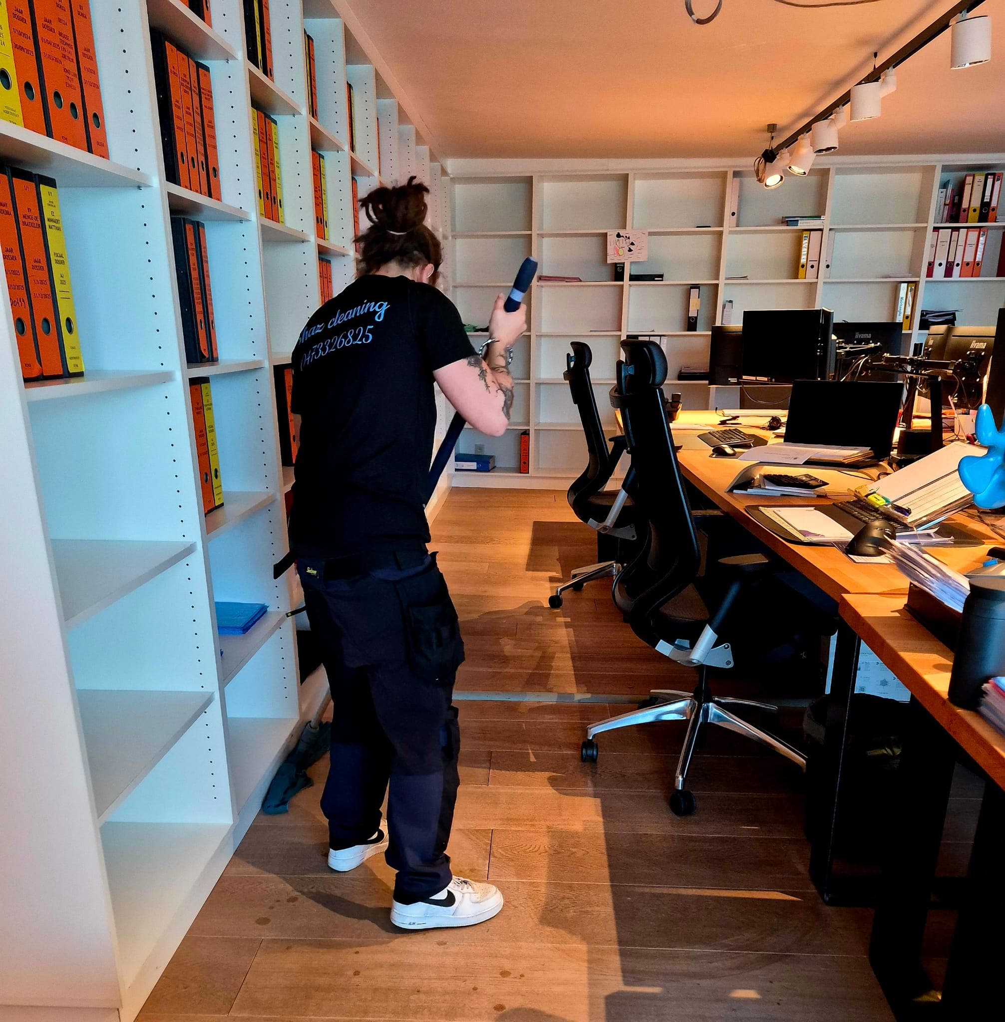 Medewerker van Shaz Cleaning stofzuigt een modern kantoor